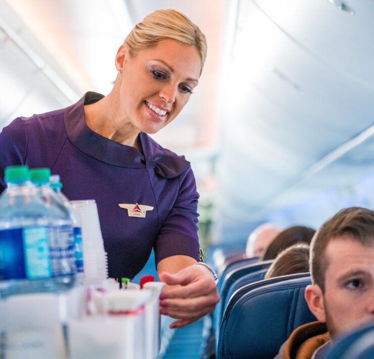 a delta air lines flight attendant performing a beverage service in the cabin