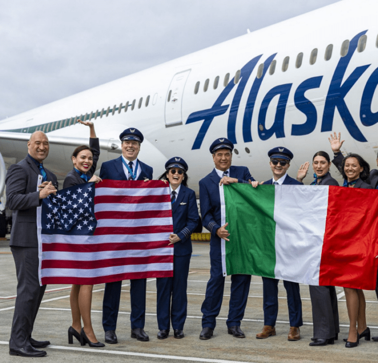 flight crew holding flags in front of an alaska airlines boeing 787