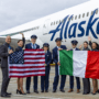 flight crew holding flags in front of an alaska airlines boeing 787