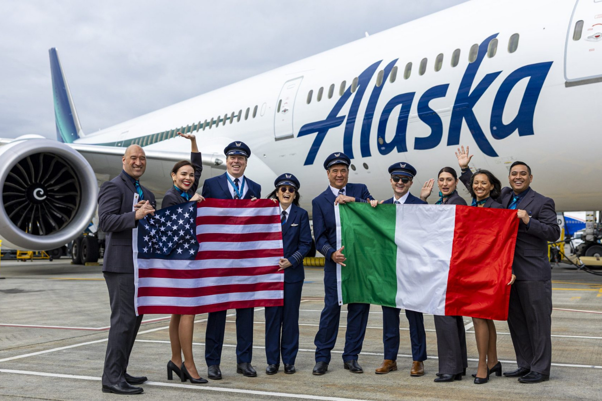 flight crew holding flags in front of an alaska airlines boeing 787