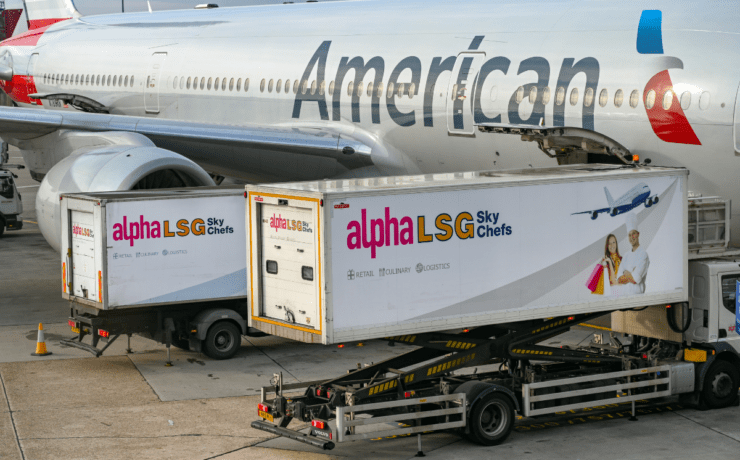 two catering trucks at the side of an American Airlines aircraft