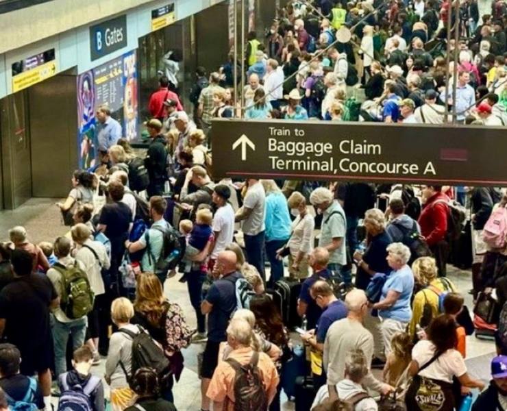 a crowd of people waiting to board a train at denver airport