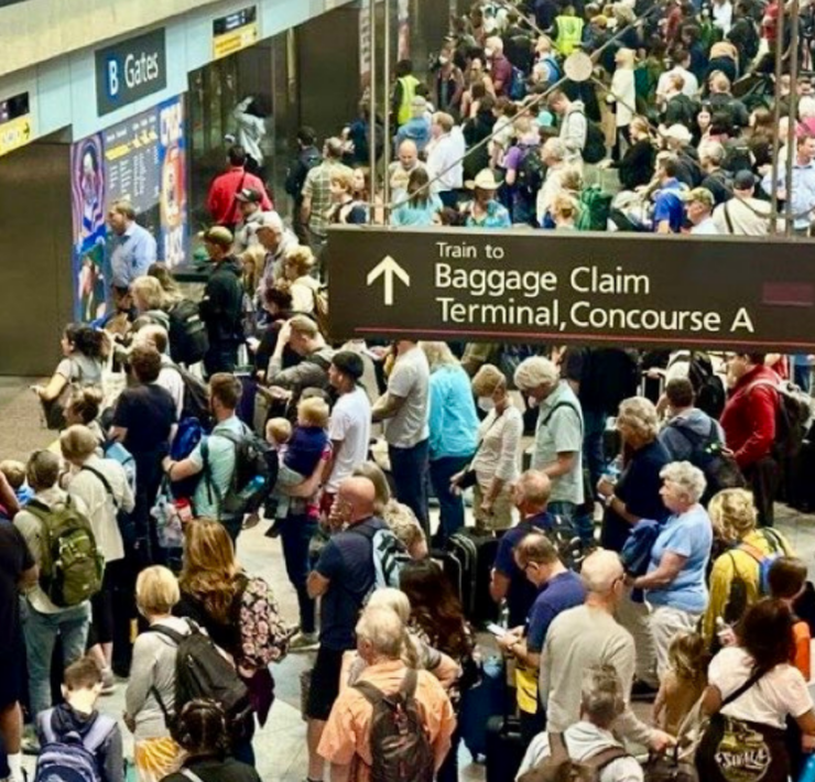 a crowd of people waiting to board a train at denver airport