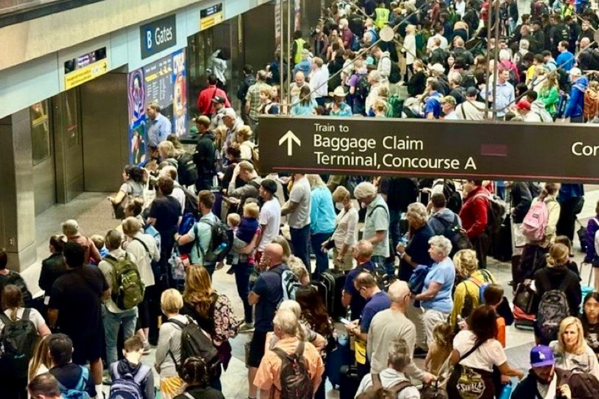 a crowd of people waiting to board a train at denver airport