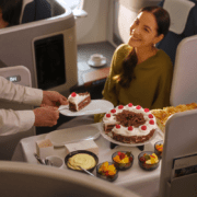 a lufthansa crew members serving a business class passenger a slice of cake