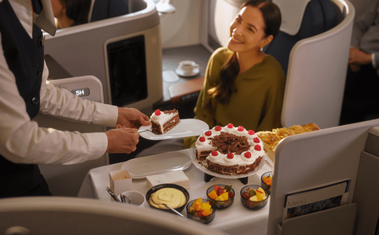 a lufthansa crew members serving a business class passenger a slice of cake
