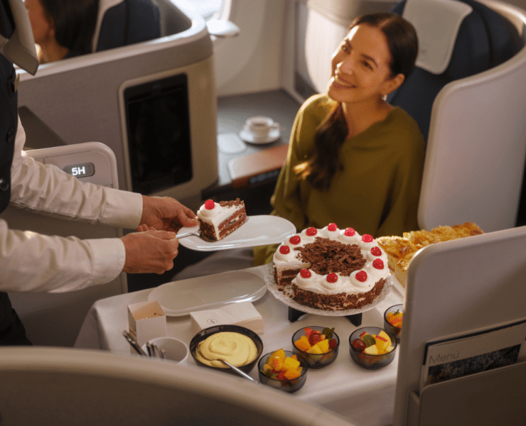 a lufthansa crew members serving a business class passenger a slice of cake