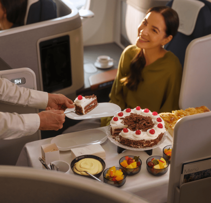 a lufthansa crew members serving a business class passenger a slice of cake